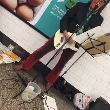 Man red hat plays guitar subway platform