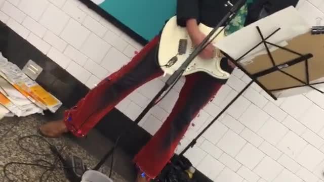 Man red hat plays guitar subway platform