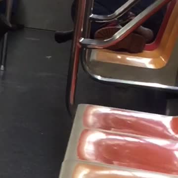 Homeless man sleeps barefoot on subway train, his boot tied to handrail