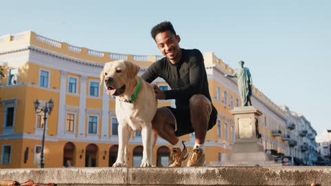 Portrait of young black man sitting with his white labrador dog