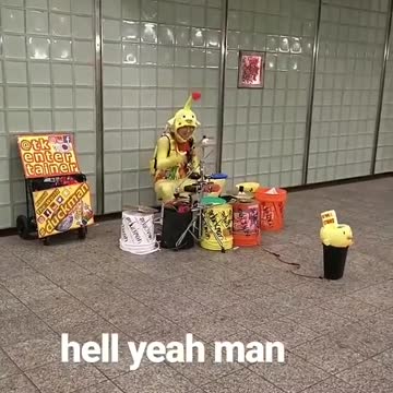 Person dressed up as alien yellow red antenna playing drums