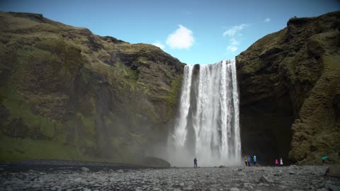 Nice view people at the base of a large waterfall