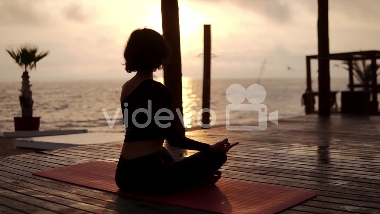 Yogi Girl Is Sitting In Lotus Pose In Front The Sea In Summer On Sunset And Meditating