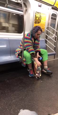 Guy wears rainbow coat on subway car