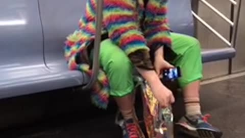 Guy wears rainbow coat on subway car