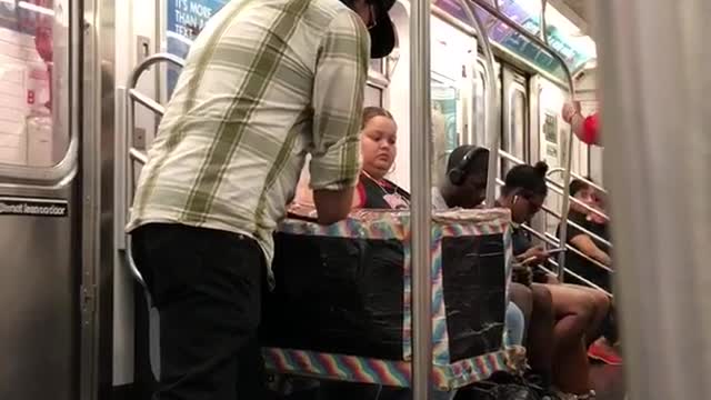 Guy performing magic out of small stroller box on subway