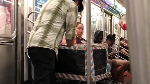 Guy performing magic out of small stroller box on subway