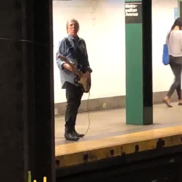 Guy denim jacket playing electric guitar subway