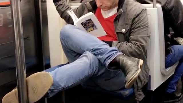 Cross legged man on subway reads book