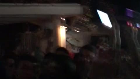 Guy in white shirt jumps into crowd while filming on phone
