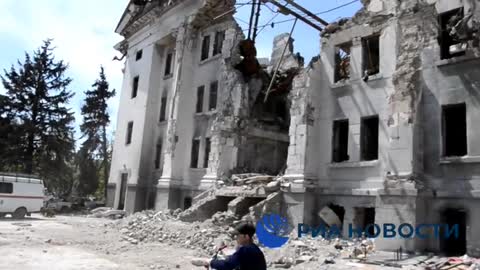 Klidný život v Mariupolu - děti jezdí na kolech u rozbombardovaného divadla