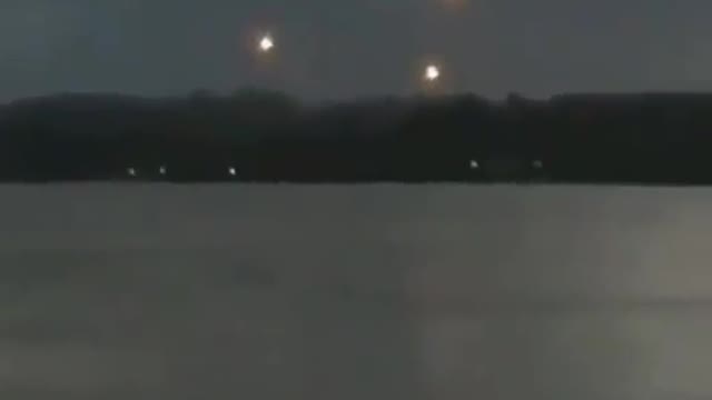 People looking at a lake, seeing lights in the sky like UFOs