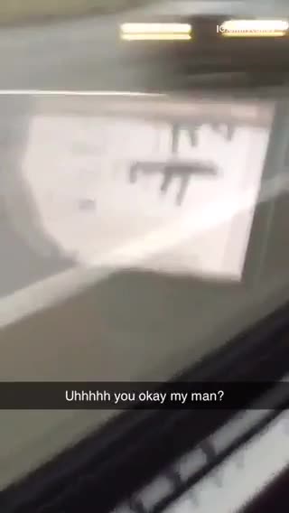 Window reflection shows man browsing guns on his laptop on bus