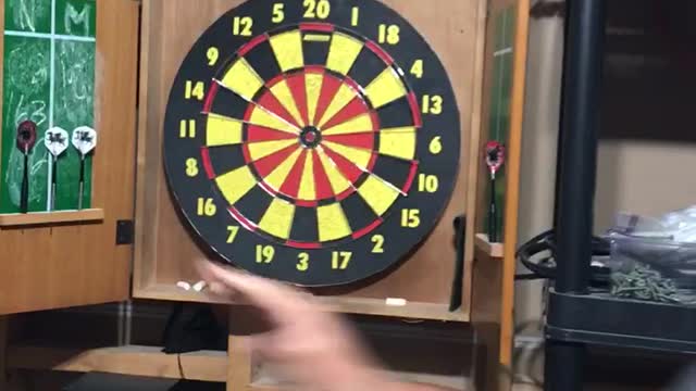 Guy in hat throws dart and almost hits a hand