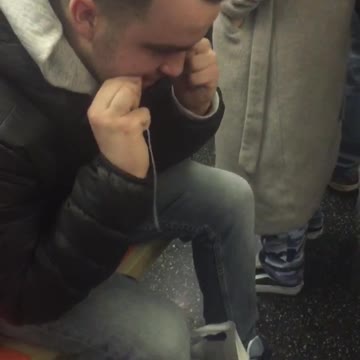 Man in leather jacket and hoodie flosses on subway