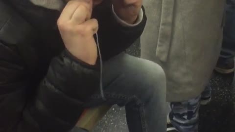 Man in leather jacket and hoodie flosses on subway