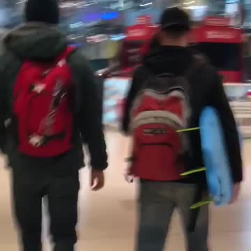 Guy carries surfboard through a mall