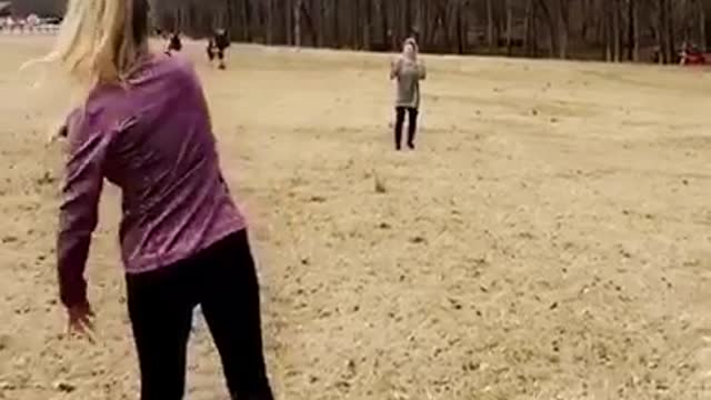 Girl purple jacket tosses football to friend green jacket falls