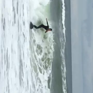 Black wet suit blue bored knocked out by wave