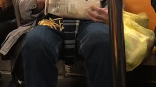 Man eats bag of french fries on subway