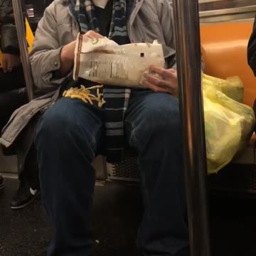 Man eats bag of french fries on subway