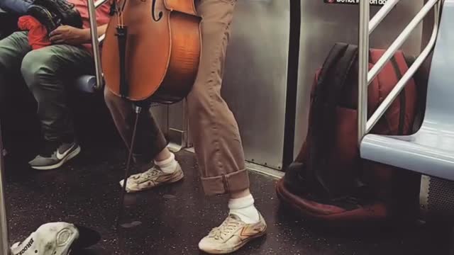 Guy purple shirt plays cello on subway train