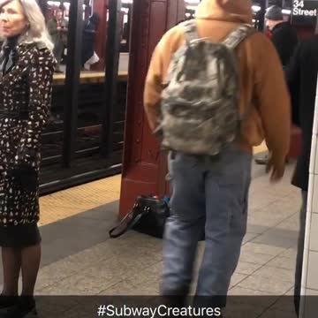 Man charging next to red pole in subway