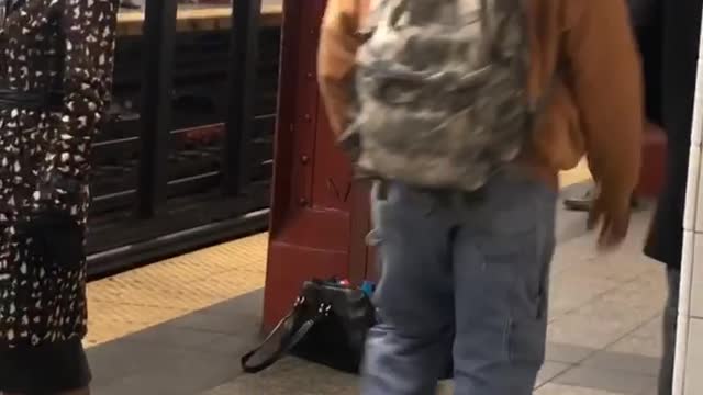 Man charging next to red pole in subway
