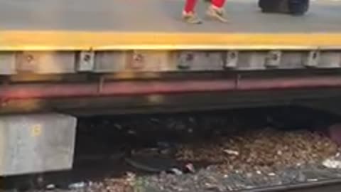 Man in red outfit giant fish on him subway platform