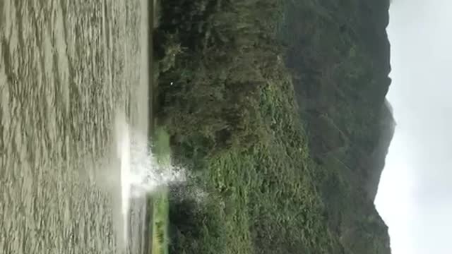 Guy does huge backflip off of water tower grassy mountains in background