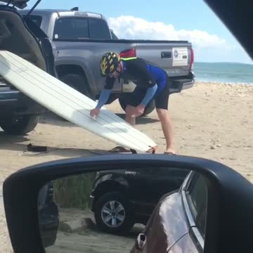 Guy cleans white surf board on car