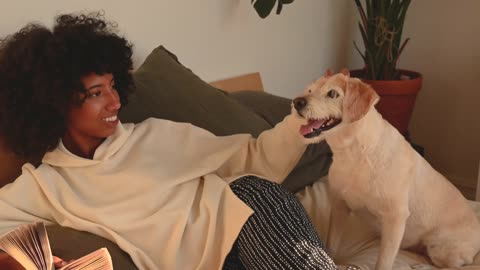A Woman Petting her Dog while Reading a Book