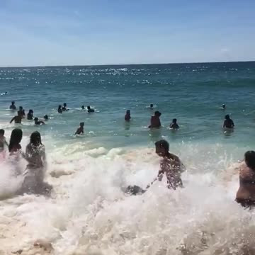 Wave knocks down people on beach