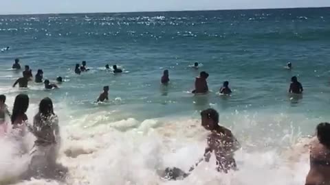 Wave knocks down people on beach