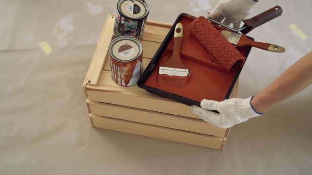 A Person Placing Red Paint With Brushes on the Top of a Wooden Box