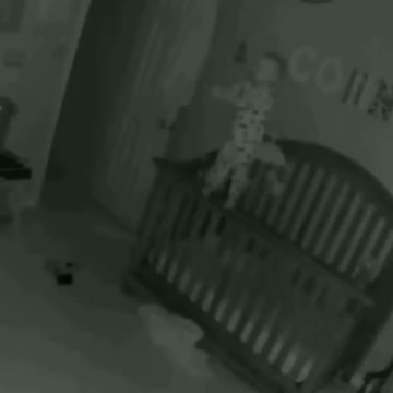 a baby who was trying to climb the fence of his bed.