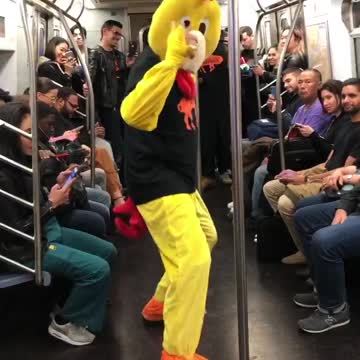 Person chicken costume dancing subway pole