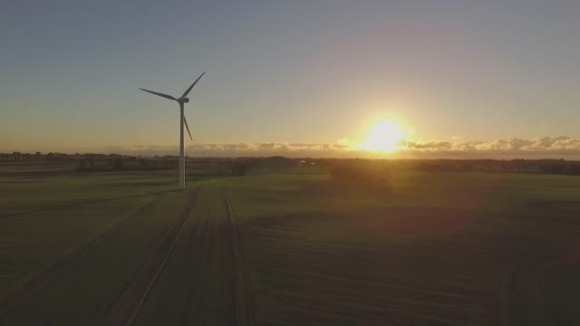 Wind turbine in the field and behind the sun shining