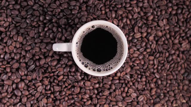 Cup of coffee on top of coffee beans