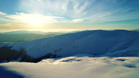 Sun illuminating the snowy relief of the mountains