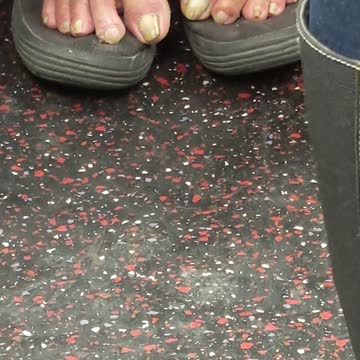Man has bare feet out on top of grey shoes