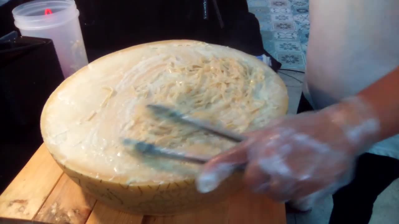 Pasta on top of a large parmesan cheese.