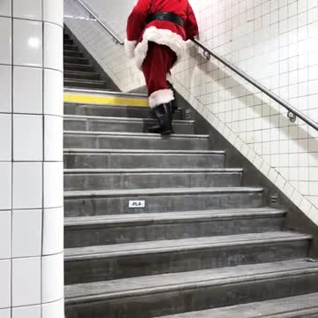 Person dressed as old santa walking up stairs slowly