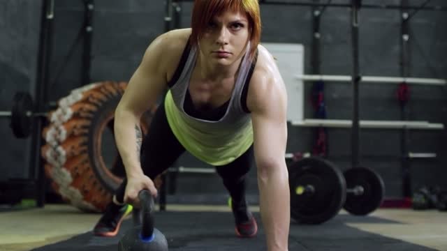 LOOK: A Woman Lifting A Cast Iron Kettle Weights While In A Push Up Exercise Position