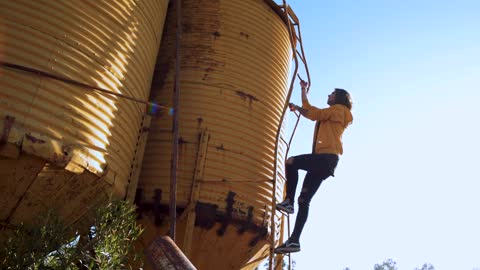 Person climbs yellow water tower