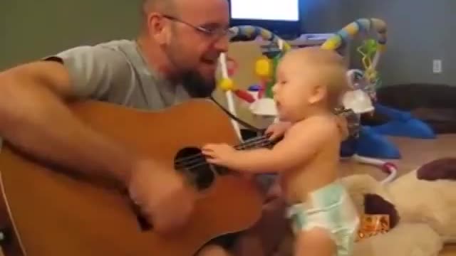 a beautiful baby dances and sings to the sound of the guitar
