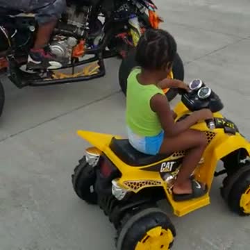 A Toddler learns to drive four Wheeler with his dad