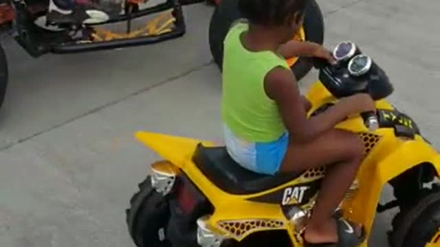 A Toddler learns to drive four Wheeler with his dad