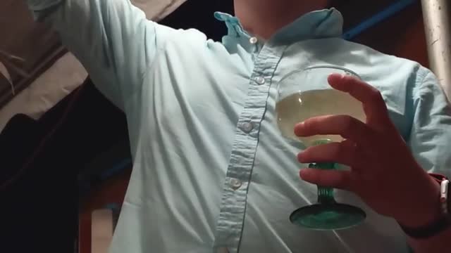 Drunk guy blue button up shirt singing idgaf with margarita drink in hand