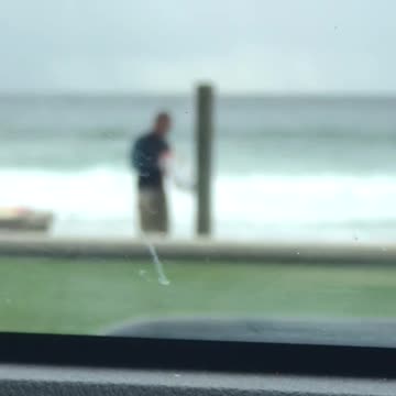 Guy washing his board at the beach shower